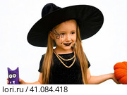 Portrait of winsome little witch smiling girl wearing a wizard hat and dressed in stylish carnival dress, looking at camera posing against white background, Halloween. Стоковое фото, фотограф Ирина Старикова / Фотобанк Лори