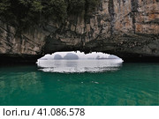 The rock hangs over the surface of the water. Through a low arched passage, you can see the islands and the ship hiding in the fog. Halong Bay. Vietnam. Close-up (2019 год). Стоковое фото, фотограф Вера Ивановна Кубарева / Фотобанк Лори