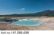 Hot natural springs flow into an amazing turquoise lake. Sulphurous deposits on the soil around. A picturesque mountain range against the blue sky. Kamchatka. The caldera of the extinct volcano Uzon. Стоковое фото, фотограф Вера Ивановна Кубарева / Фотобанк Лори
