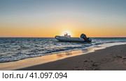 Dawn on the Red Sea. The sun is shining from behind a motorboat bobbing on the surf. Foam on a sandy beach. The sky is highlighted in orange. Egypt. Стоковое фото, фотограф Вера Ивановна Кубарева / Фотобанк Лори