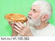 a handsome elderly man with a gray beard holds a plate of hot pancakes in his hands. Стоковое фото, фотограф Акиньшин Владимир / Фотобанк Лори