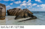 Picturesque granite boulders with smoothed folded slopes near the ocean shore. Turquoise water and blue sky with clouds. Seychelles. La Digue. Anse Source D’Argent beach. Стоковое фото, фотограф Вера Ивановна Кубарева / Фотобанк Лори