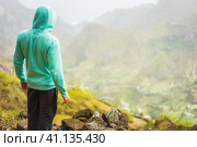Tourist in hoodie in front of rural landscape with mountains, on the way of the Paul Valley. Santo Antao Island, Cape Verde. Стоковое фото, фотограф Igor Tichonow / Фотобанк Лори
