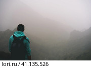 Traveler in hoodie in front of rural landscape with mountains and the ravine of Paul Valley. Santo Antao Island, Cape Verde. Стоковое фото, фотограф Igor Tichonow / Фотобанк Лори