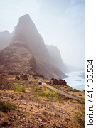 Aranhas mountain peak in the valley with house ruins and stony hiking path going up the mountain from Ponta do Sol to Cruzinha village. Santo Antao Island, Cape Verde. Стоковое фото, фотограф Igor Tichonow / Фотобанк Лори
