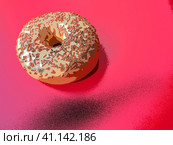 A doughnut or donut. A type of leavened fried dough. Sweet snack that can be homemade or purchased in bakeries, supermarkets, food stalls. Delicious pie with light icing on a red background, illusion. Стоковая иллюстрация, иллюстратор Юлия Петровская / Фотобанк Лори