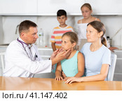 Man doctor examines throat and lymph nodes of small girl patient at home. Стоковое фото, фотограф Яков Филимонов / Фотобанк Лори
