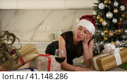 young girl in santa hat is sitting in kitchen. she is sad and upset. Стоковое видео, видеограф Яков Филимонов / Фотобанк Лори