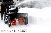 Snowblower removes snow, a man cleans the yard outside. Стоковое фото, фотограф Igor Skripachev / Фотобанк Лори