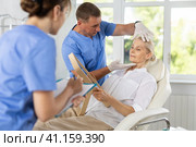 Male beautician, together with a nurse, examines the face of an mature woman and plans facelift procedures. Стоковое фото, фотограф Яков Филимонов / Фотобанк Лори