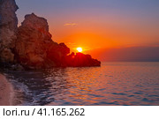 Beautiful sunset on the sea coast. Rocky coast of the sea, the leaving bright sun behind the mountain. Стоковое фото, фотограф Коханова Наталья / Фотобанк Лори