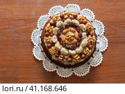 Top view of a beautiful appetizing homemade cake decorated with nuts on a handmade lace napkin on a wooden table. Family celebration, holiday, treat, birthday. Flat lay, close-up, mock up. Стоковое фото, фотограф Виктория Катьянова / Фотобанк Лори