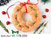 Bread Christmas wreath with cheese topped with rosemary and red berries on the white table. Festive monkey bread. Стоковое фото, фотограф Оксана Чаюн / Фотобанк Лори