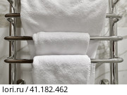 White terry towels hanging on a heated towel rail in the bathroom. Стоковое фото, фотограф Володина Ольга / Фотобанк Лори
