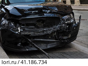 Seriously damaged black car after road accident is parked on the street. Серьезно поврежденный черный автомобиль после дорожно-транспортного происшествия припаркован на улице. Стоковое фото, фотограф Дмитрий Березнев / Фотобанк Лори