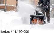 Snowblower removes snow, a man cleans the yard outside. Стоковое фото, фотограф Igor Skripachev / Фотобанк Лори