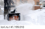 Snowblower removes snow, a man cleans the yard outside. Стоковое фото, фотограф Igor Skripachev / Фотобанк Лори