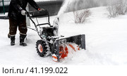 Snowblower removes snow, a man cleans the yard outside. Стоковое фото, фотограф Igor Skripachev / Фотобанк Лори