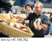 Couple chooses sweet puffs in bakery. Стоковое фото, фотограф Татьяна Яцевич / Фотобанк Лори