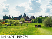 People walking on grass field in park in sunny spring day. On the background is wooden palace or castle of Tsar Aleksey Mikhailovich in Kolomenskoye. Редакционное фото, фотограф Константин Григорьев / Фотобанк Лори
