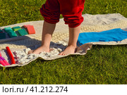 Children's feet walk on an orthopedic massage diy mat with surfaces of various shapes and tactility. grass, cones, acorns - texture details. Prevention and treatment of flat feet. Стоковое фото, фотограф Ирина Старикова / Фотобанк Лори