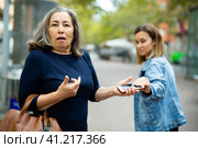Female thief trying to snatch phone of elderly woman outdoors. Стоковое фото, фотограф Яков Филимонов / Фотобанк Лори