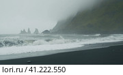 The black sand beach of Reynisfjara with waves hitting the shore on foggy rainy stormy day Vik, Icel. Стоковое фото, фотограф Igor Tichonow / Фотобанк Лори