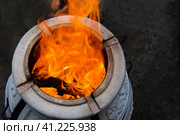Firewood is burned in a tandoor heating it before cooking meat. Evening in the garden. Tandoor oven roaster, a special spherical or pitcher-shaped grill for cooking a variety of food among the peoples of Asia. В тандыре сжигают дрова, разогревая их перед приготовлением шашлыка на ночь. Тандыр - это специальный гриль сферической или кувшинообразной формы для приготовления разнообразных блюд у народов Азии. Стоковое фото, фотограф Дмитрий Березнев / Фотобанк Лори