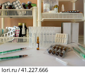 Syringes, ampoules and saline solution are on the table. In the background you can see shelves with various medicines. Medical background with medicines, tinctures, syringes. Стоковое фото, фотограф Бузмакова Светлана / Фотобанк Лори