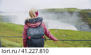 Tourist woman looking at Gullfoss waterfall the famous attraction and landmark destination on Iceland on the Golden Circle. Стоковое фото, фотограф Igor Tichonow / Фотобанк Лори
