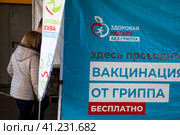 Люди записываются на прием в мобильный пункт бесплатной вакцинации от гриппа в специальном автомобиле скорой помощи у метро в городе Москве, Россия (2023 год). Редакционное фото, фотограф Николай Винокуров / Фотобанк Лори