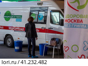 Женщина ждет своей очерди на вакцинацию у мобильного пункта бесплатной вакцинации от гриппа в специальном автомобиле скорой помощи в городе Москве, Россия (2023 год). Редакционное фото, фотограф Николай Винокуров / Фотобанк Лори