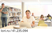 View on bored young caucasian latina student with a laptop in the school library. Стоковое видео, видеограф Яков Филимонов / Фотобанк Лори