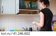 The girl lays out clean dishes in the cupboard for drying dishes in the kitchen (2021 год). Редакционное видео, видеограф Алексей Гекало / Фотобанк Лори