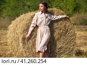 Young beautiful brunette model in a beige dress posing against the background of a mowed wheat field. Стоковое фото, фотограф Андрей Аркуша / Фотобанк Лори