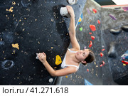 Female fitness climber training at bouldering gym. Young woman rise up on artificial climbing wall. Стоковое фото, фотограф Яков Филимонов / Фотобанк Лори