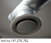 Extractor hood in a public toilet. Round metal pipe with gray air extractor. Engineering ventilation systems. Galvanized pipes under the ceiling of the room. Plastic round tip. Стоковое фото, фотограф Юлия Петровская / Фотобанк Лори