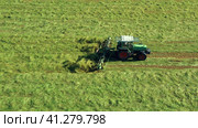 A tractor turns up the grass, aerial view. Стоковое видео, видеограф Артем Лукин / Фотобанк Лори