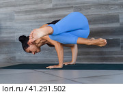 side crow pose variation parsva bacasana yoga with ukrainian woman making it indoors. Стоковое фото, фотограф Татьяна Терехина / Фотобанк Лори