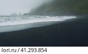 The black sand beach of Reynisfjara with waves hitting the shore on foggy rainy stormy day Vik, Icel. Стоковое видео, видеограф Igor Tichonow / Фотобанк Лори