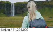 Close up of Woman with backpack enjoying famous Seljalandsfoss waterfall Iceland. Стоковое видео, видеограф Igor Tichonow / Фотобанк Лори