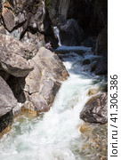 Siberia. Buryatia. Arshan resort. Popular place among tourists is waterfall on mountain river Kyngagra. Tourist sits on rock, admires mountain stream and eats cedar nuts. Summer activity outdoors and travel. Стоковое фото, фотограф Виктория Катьянова / Фотобанк Лори
