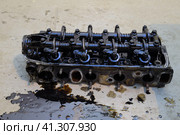 The head of the block of cylinders. The head of the block of cylinders removed from the engine for repair. Parts in engine oil. Car engine repair in the service. Стоковое фото, фотограф Леонид Еремейчук / Фотобанк Лори