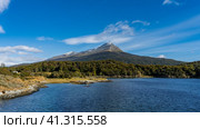 On the shore of a beautiful blue lake grows a forest, yellowed grass. Mountain on the background of azure sky and clouds. Lapataia Bay. Argentina. Tierra del Fuego National Park. Argentina. Стоковое фото, фотограф Вера Ивановна Кубарева / Фотобанк Лори