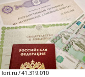 Государственный сертификат материнский (семейный) капитал, свидетельство о рождении, российский паспорт и деньги (2023 год). Редакционное фото, фотограф Цибаев Алексей / Фотобанк Лори