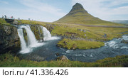 Kirkjufellsfoss and Kirkjufell in northern Iceland Unrecognized toursit people on the bridge. Стоковое видео, видеограф Igor Tichonow / Фотобанк Лори