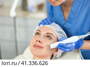 Young girl getting facial rf-lifting procedure of smoothes wrinkles and tightens skin on face in beauty salon. Concept of professional cosmetology. Стоковое фото, фотограф Яков Филимонов / Фотобанк Лори