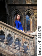 Portrait young beautiful brunette woman in blue dress posing against the backdrop of an old castle in the Gothic style. Стоковое фото, фотограф Андрей Аркуша / Фотобанк Лори