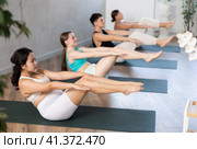 Asian girl performs boat asana - Paripurna navasana in group class. Стоковое фото, фотограф Яков Филимонов / Фотобанк Лори
