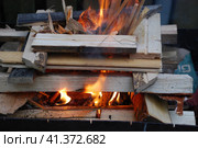 Огонь полыхает между дровами, сложенными друг на друга. Несколько сосновых и березовых поленьев сложены в квадратную башню, в центре которой ярко горят дрова и щепа. Стоковое фото, фотограф Andrew_Swarga / Фотобанк Лори
